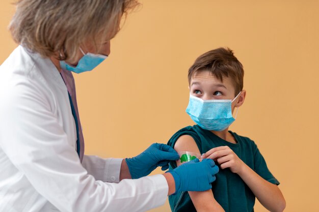 Gros plan sur un enfant et un médecin portant des masques