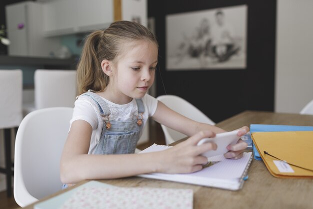 Gros plan d'une enfant de sexe féminin de race blanche jouant à un jeu sur son téléphone à la maison