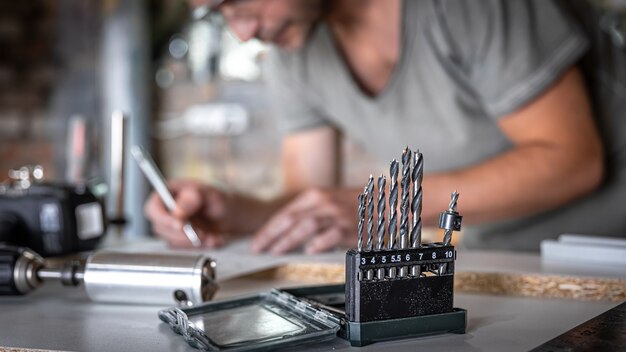 Gros plan d'un ensemble de perceuses à bois sur une table de travail d'un menuisier dans un atelier.