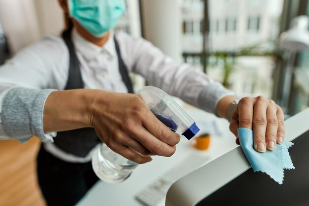 Gros plan d'une femme d'affaires nettoyant son ordinateur tout en travaillant au bureau