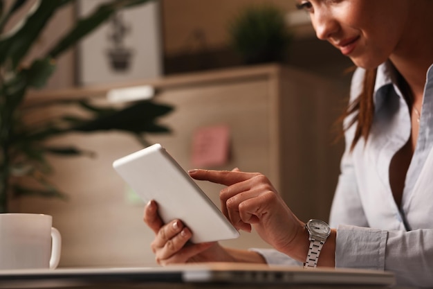 Gros plan sur une femme d'affaires souriante naviguant sur Internet sur un pavé tactile au travail