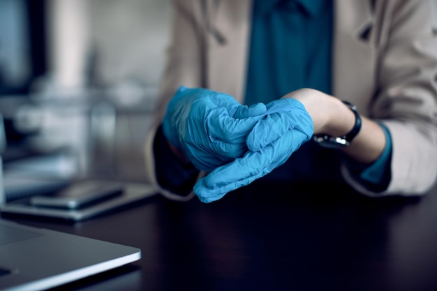 Gros Plan Sur Une Femme D'affaires Utilisant Des Gants De Protection Au Bureau En Raison De La Pandémie De Covid19