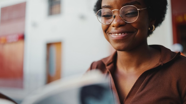 Gros plan sur une femme africaine dans une ambiance détendue lisant un boo intéressant