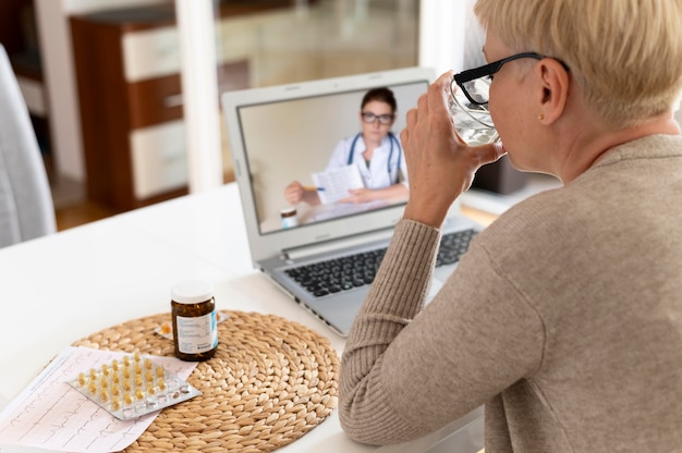 Gros plan sur une femme âgée parlant à un médecin en ligne