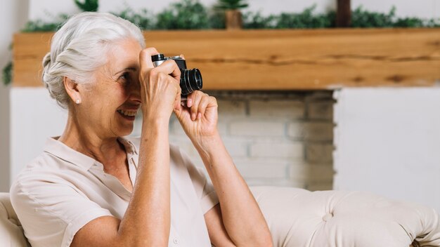 Gros plan d&#39;une femme âgée souriante prenant une photo de la caméra