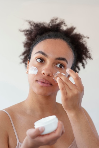 Gros plan femme à l'aide de crème pour le visage