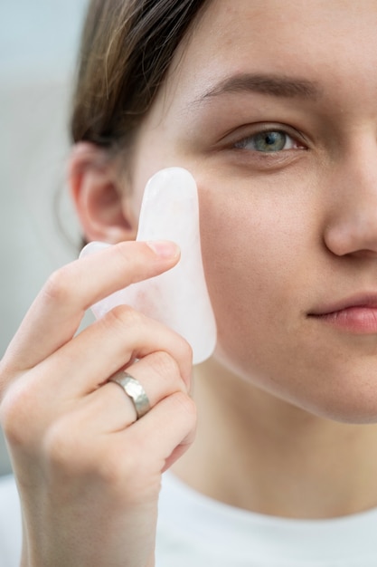 Gros plan femme à l'aide de l'outil gua sha