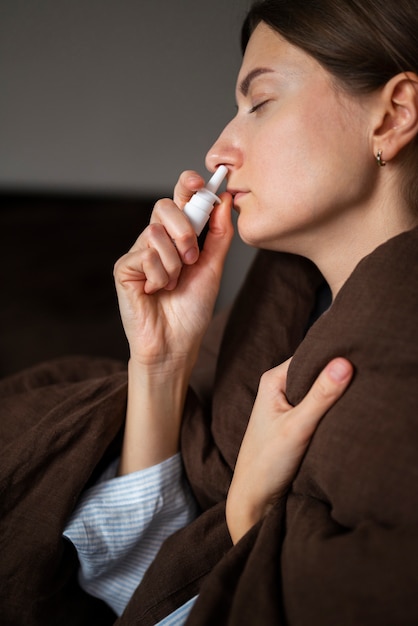 Gros plan femme à l'aide d'un spray nasal