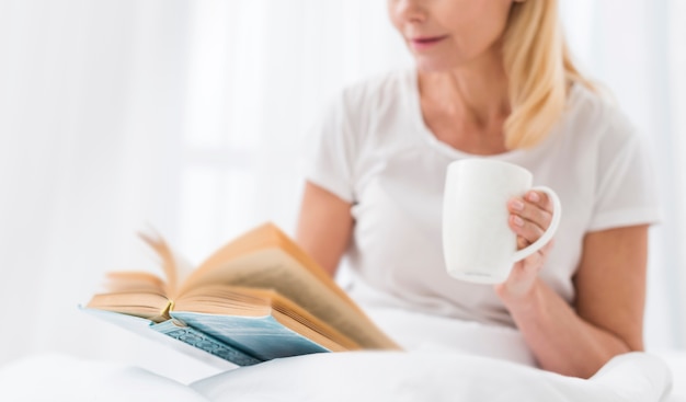 Gros plan, femme aînée, lecture livre, dans lit