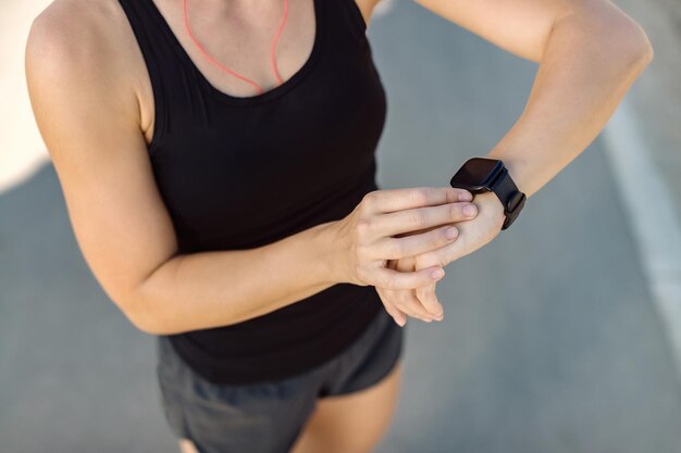 Gros plan d'une femme athlétique à l'aide d'un tracker de fitness à l'extérieur