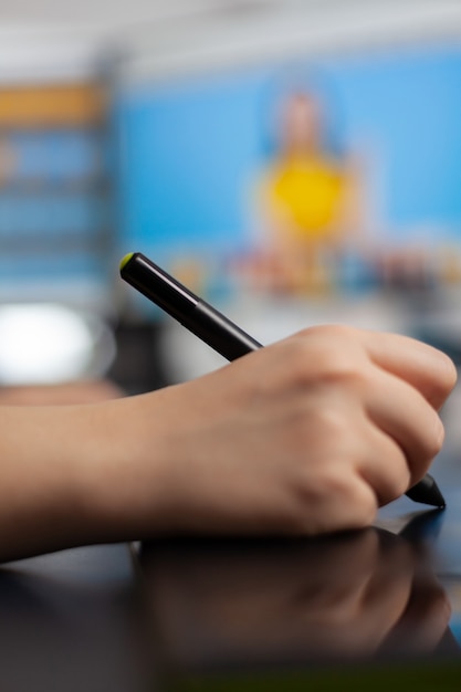 Gros plan sur une femme de couleur retouchoir tenant un stylet se déplaçant sur une tablette graphique éditant la photo du client à l'aide d'un ordinateur avec deux écrans