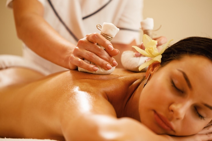 Photo gratuit gros plan d'une femme détendue se faisant masser le dos avec des boules à base de plantes au spa de santé