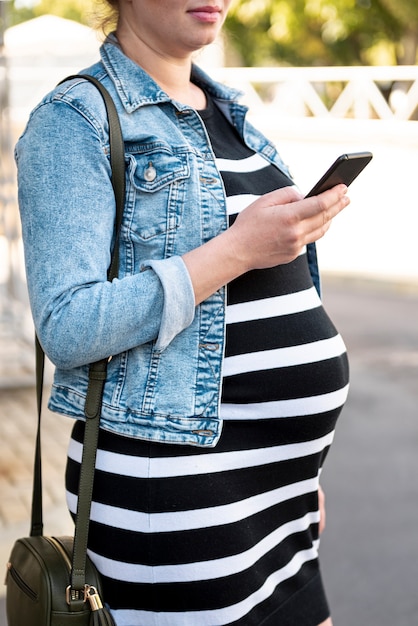 Photo gratuite gros plan femme enceinte avec smartphone à l'extérieur