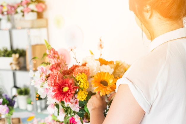 Gros plan, de, femme fleuriste, main, arrangeant des fleurs colorées