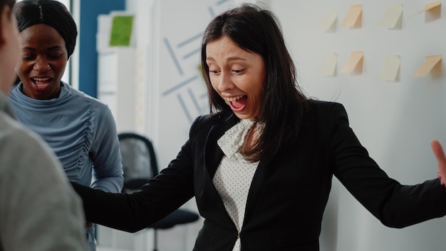 Gros plan sur une femme heureuse gagnant un jeu au baby-foot, jouant avec des collègues de bureau après le travail. Personne profitant de temps libre et de boissons pour faire une activité amusante avec des collègues après les heures.