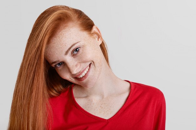 Gros plan de femme heureuse avec des taches de rousseur aux longs cheveux roux