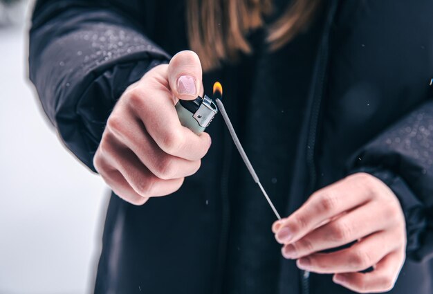 Gros plan d'une femme mettant le feu à un cierge magique avec un briquet