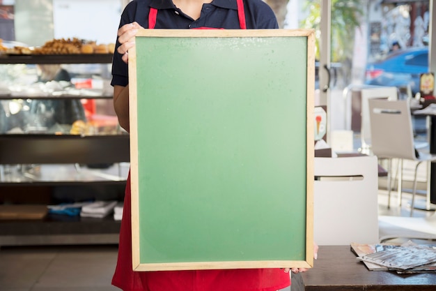 Photo gratuite gros plan de femme montrant un tableau de menu vide dans un café