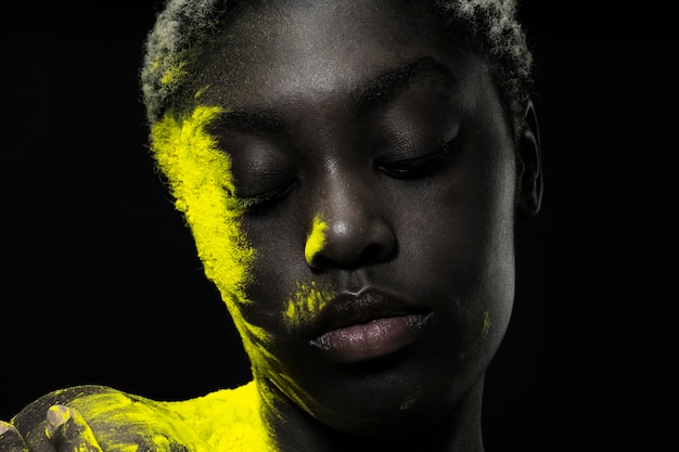 Gros plan femme noire posant avec de la poudre jaune