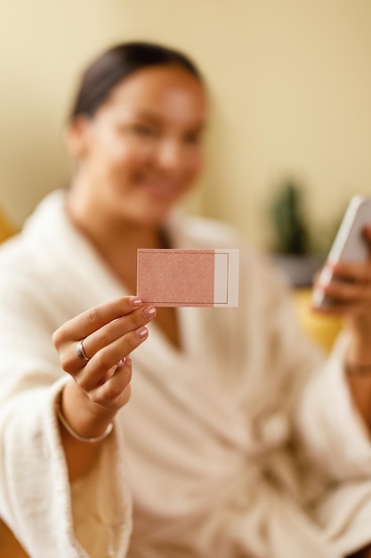 Gros plan d'une femme en peignoir tenant une carte de visite vierge tout en dépensant au salon de spa