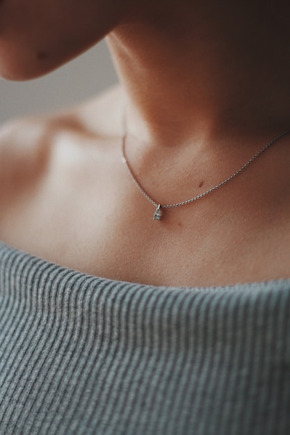 Gros plan d'une femme portant un beau collier en argent avec un pendentif