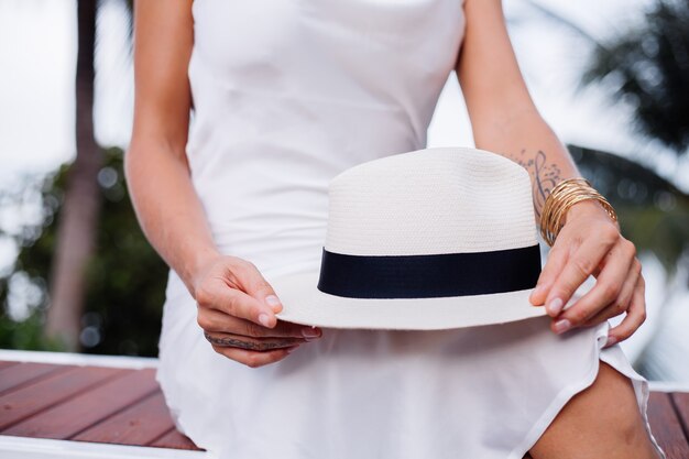 Gros plan femme en robe ajustée en soie avec chapeau blanc classique