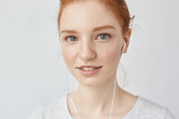 Gros plan d'une femme rousse au casque souriant.