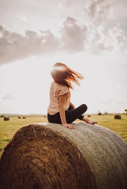 Gros plan d'une femme seule assise sur un tas d'herbe par une belle journée ensoleillée