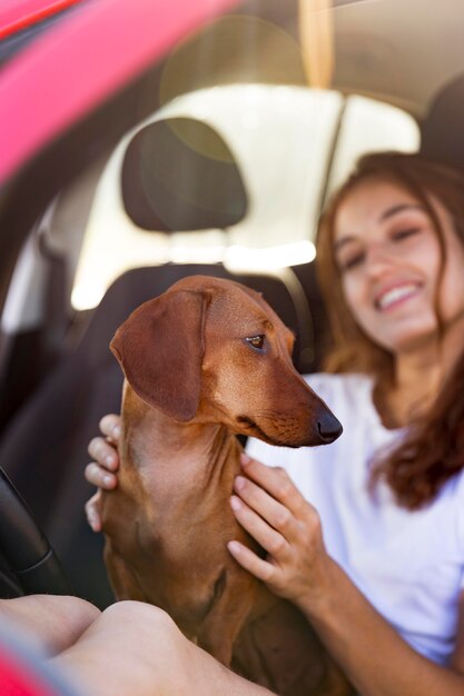 Gros plan femme souriante avec chien mignon en voiture