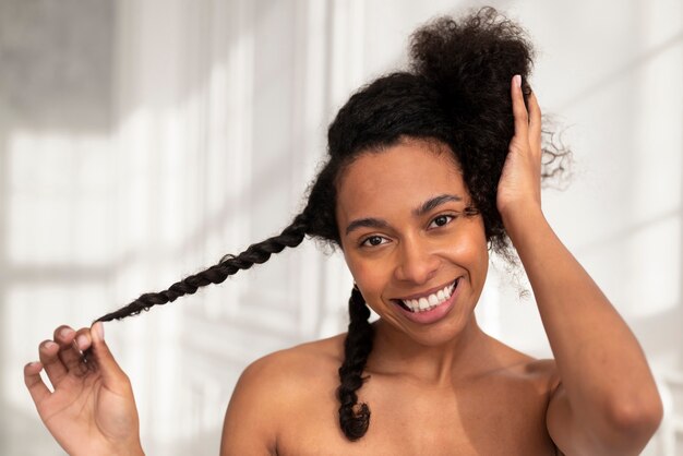 Gros plan femme souriante coiffant les cheveux