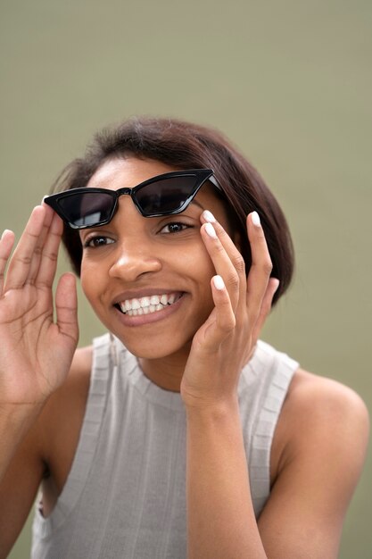 Gros plan femme souriante avec des lunettes de soleil