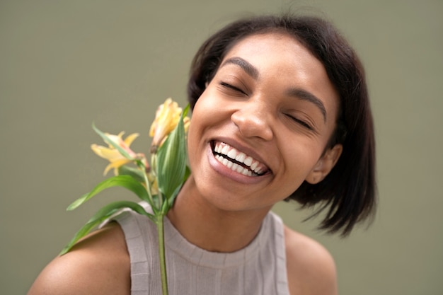 Gros plan femme souriante posant avec fleur