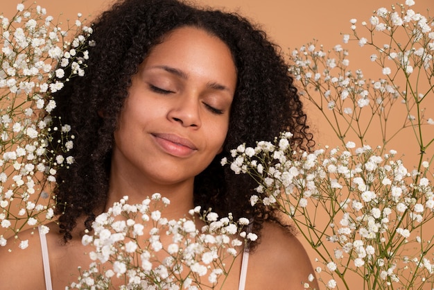 Gros plan femme souriante posant avec des fleurs