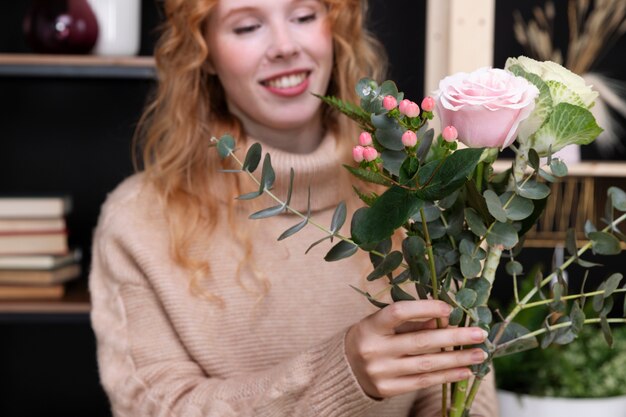 Gros plan femme souriante tenant des fleurs