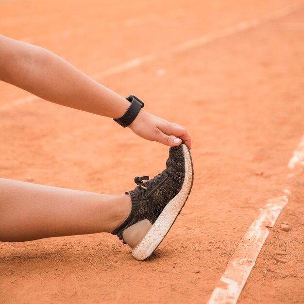 Gros plan d&#39;une femme sportive qui s&#39;étend sur la piste du stade