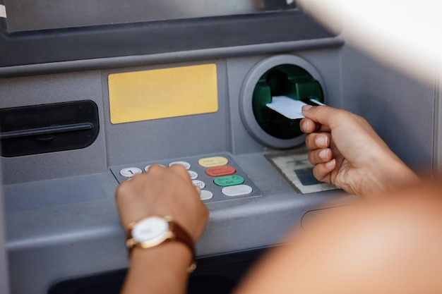 Gros plan sur une femme tapant un code PIN tout en retirant de l'argent d'un guichet automatique