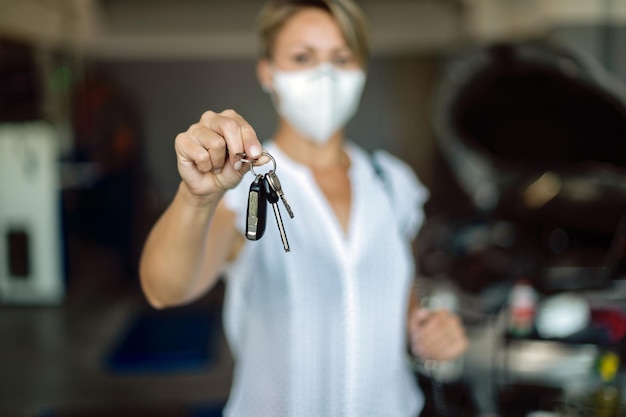 Gros plan sur une femme tenant des clés de voiture dans un atelier de réparation automobile