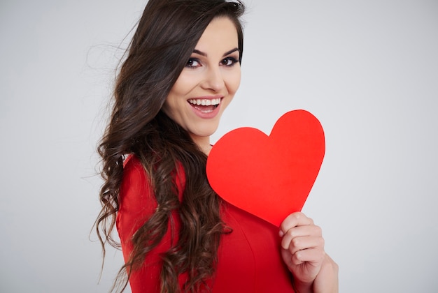 Gros plan d'une femme tenant un coeur de papier rouge