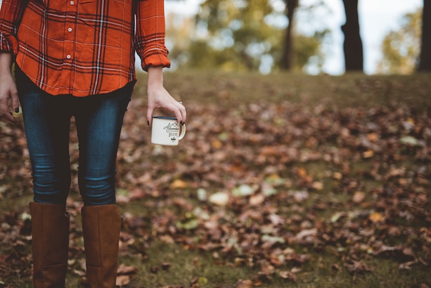 Gros plan d'une femme tenant une tasse avec un arrière-plan flou