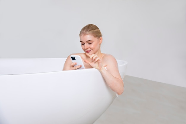 Gros plan femme tenant un téléphone dans la baignoire