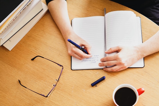 Gros plan d'une femme travaillant ou étudiant à domicile avec une tasse de café rouge à proximité