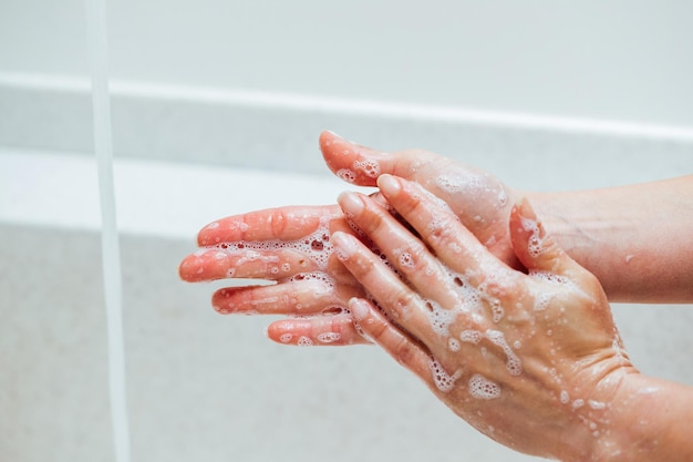 Gros plan d'une femme utilisant du savon en se serrant les mains dans la salle de bain