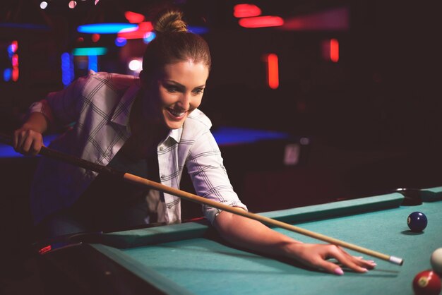 Gros plan sur la femme visant à jouer au jeu de billard