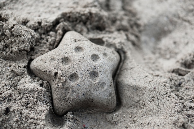 Gros plan d'une figure en forme d'étoile de mer faite avec du sable humide