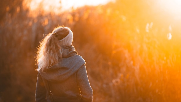 Gros plan d'une fille avec des cheveux attachés et un bandeau dans des vêtements chauds dans la forêt. Chute au soleil