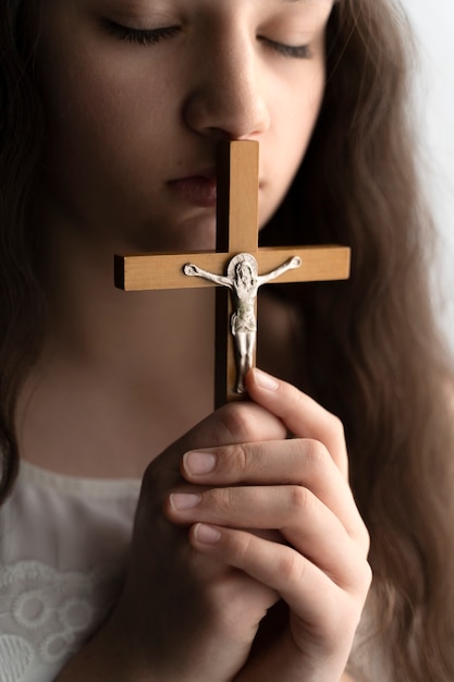 Gros plan fille chrétienne priant avec crucifix