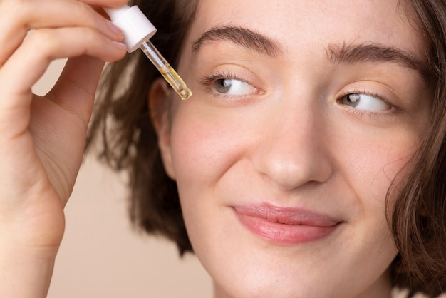 Gros plan fille souriante à l'aide de sérum pour le visage