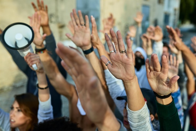 Gros plan sur une foule de manifestants les bras levés manifestant dans les rues