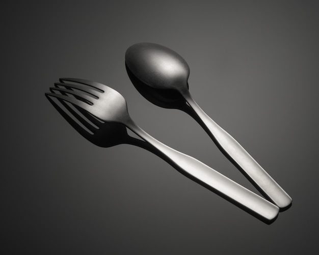 Gros plan d'une fourchette en métal et d'une cuillère isolée sur une table grise
