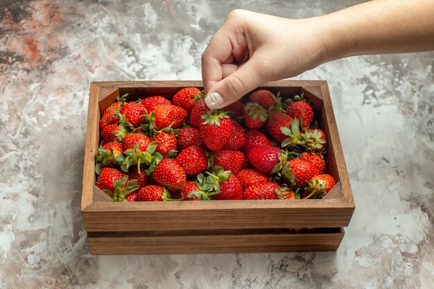 Gros plan sur des fraises fraîches dans une petite boîte en bois marron